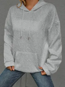 Vista detallada de la sudadera gris para mujer con letras en relieve texturizadas y bolsillo.