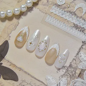 Vista detallada de uñas postizas barrocas vintage con encaje en relieve, perlas y gemas.