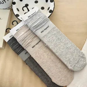 Detail shot of ribbed mid-calf stacked socks in various neutral colors, soft cotton texture.