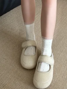 Vue en gros plan de chaussettes transparentes à pois associées à des chaussures plates à velcro.