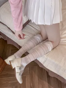 Detail shot of sheer striped calf socks with cute bows and Mary Jane shoes on bed.
