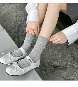 Detail view of grey ribbed slouch socks paired with white ballet flats, showing texture.