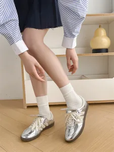 Detailansicht von einfarbigen weißen Socken kombiniert mit stylischen Sneakers in Silber.