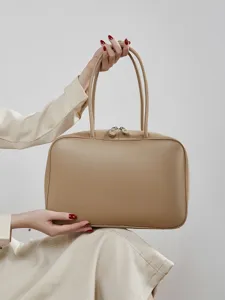 Elegant beige leather tote bag for women, classic handbag with double handles and top zipper.
