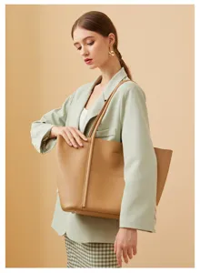 Primer plano detallado del elegante bolso tote de cuero marrón con un blazer elegante.