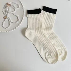 Comfortable white ribbed crew socks for women featuring stylish black cuffs and mesh.