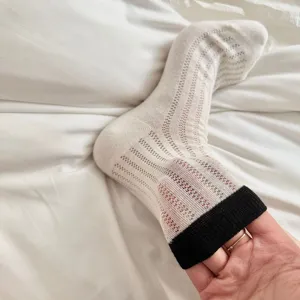 Detail shot of women's mid-tube slouch socks with hollow knit pattern and contrasting black cuff.