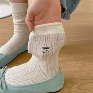 Close-up detail of white ribbed hollow socks featuring sweet black bow embroidery.