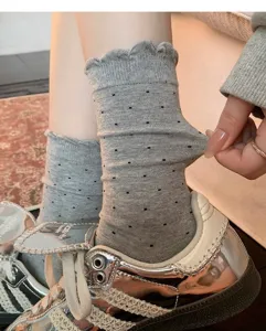 Grey cotton mid-tube socks with black polka dots and ruffled cuffs, stylish detail view.