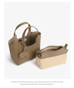 Detailed view of casual taupe leather tote bag and canvas pouch set with cute elephant charm.