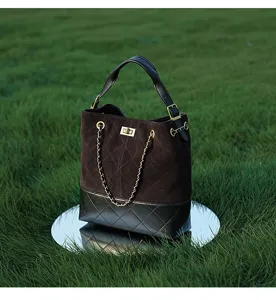 Vista dettagliata della borsa a secchiello in camoscio trapuntato con catena e chiusura.