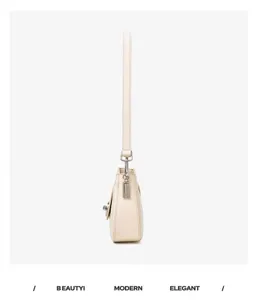 Side detail view of the elegant beige leather crossbody bag featuring fine metal hardware and smooth finish.