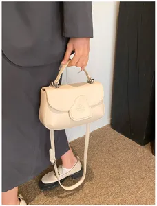 Detailaufnahme der schicken beigen PU-Leder-Umhängetasche mit Herzklappe und Trageriemen.