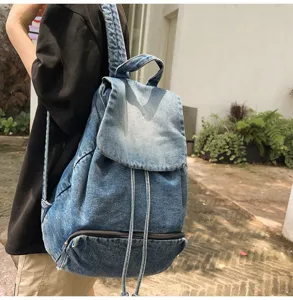 Detailed shot of retro blue denim backpack showing canvas texture, drawstring and zipper pocket.