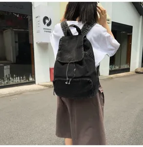 Detail shot of black denim backpack, casual street style showcasing rear view and pocket details.