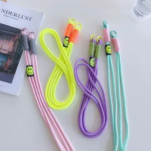 Detailed view of colorful phone lanyards with smiley tags and double clasps on white table.