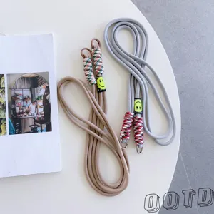 Crossbody mobile phone lanyard with colorful woven design and cute smiley face charm.