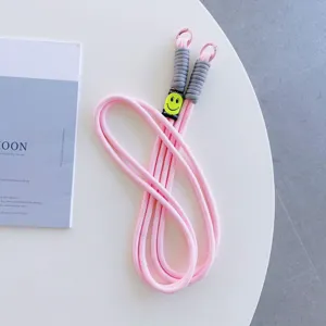 Pink phone lanyard crossbody strap with grey braided handle and cute smiley face charm detail.