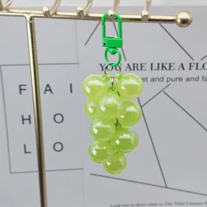 Close-up detail of green acrylic grape keychain hanging on display stand, fashion accessory.