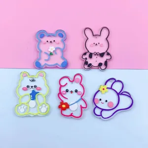 Closeup of 5 cute cartoon bear and rabbit acrylic transparent pendants for DIY crafts.