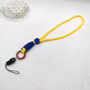 Détail de la lanière de téléphone tressée à la main avec cordon bicolore, boucle et anneau métal.