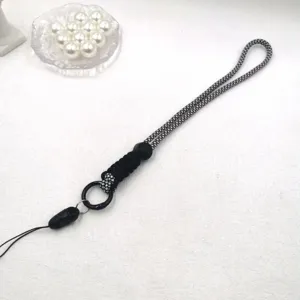 Gros plan détaillé de la lanière de téléphone tressée noir et blanc avec boucle et anneau.