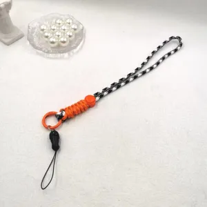 Détail de lanière de téléphone tressée, motif pied-de-poule noir blanc et cordon orange, réglable.