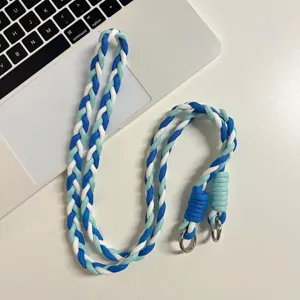 Lanière de téléphone tressée bleue et blanche en gros plan avec anneaux métalliques.
