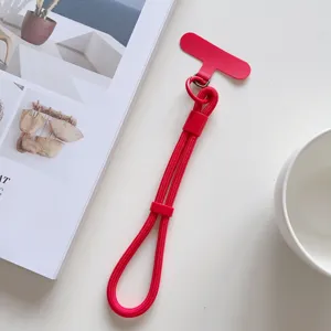 Primer plano de la correa de muñeca roja para teléfono con hebilla ajustable y almohadilla.