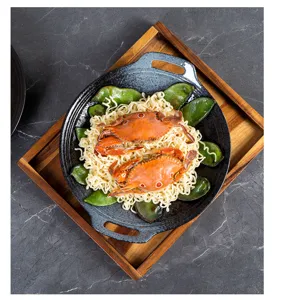Close-up detail of Japanese ceramic dual-handle baking plate serving delicious meal setup.