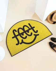 Alfombra de entrada amarilla semicircular con texto pies y diseño de cara sonriente.