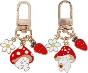 Detailed close-up of gold-tone metal keychain featuring cute mushroom, daisy and strawberry charms.