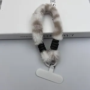 Dettaglio del laccetto per telefono in peluche leopardato, polsiera soffice con accento intrecciato.