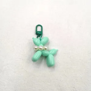 Close-up of mint green balloon dog acrylic keychain with pearl collar and green clasp.