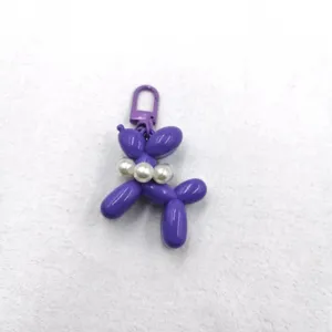 Detailed view of cute purple balloon dog acrylic keychain with pearl decor for bags.