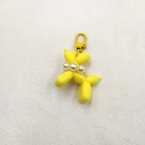 Yellow balloon dog keychain with pearl charm, cute acrylic pendant for bags and phone cases.