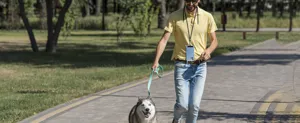 Outdoor lifestyle detail view of a durable crossbody phone lanyard in use while walking a dog.