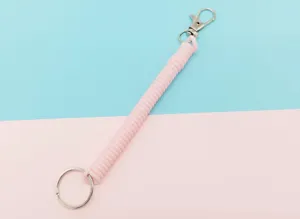 Vue détaillée du porte-clés à spirale rétractable rose avec fermoir et anneau en métal.