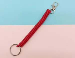 Gros plan sur le détail du porte-clés à ressort en plastique rouge avec anneau et mousqueton.