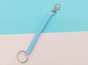 Détail de porte-clés à ressort télescopique en plastique bleu clair, cordon extensible pour clés.