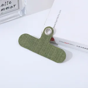 Vista detallada de la lengüeta para teléfono de tela verde con un ojal metálico resistente.