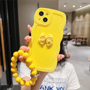 Gros plan détaillé de la coque de téléphone en silicone jaune bonbon avec nœud et bracelet perlé.