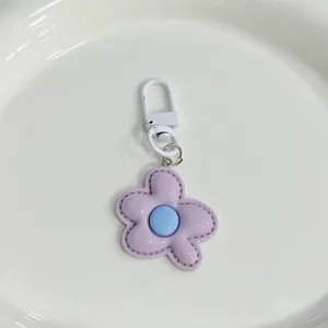 Cute pastel flower keychain detail, purple and blue resin pendant with white metal hook.