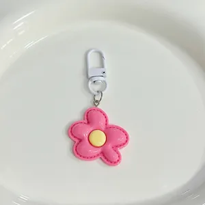Close-up of the cute pink flower keychain detail, featuring a vibrant yellow center and white clasp.