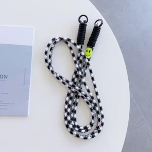 Black and white houndstooth phone lanyard with metal clips and yellow smiley face charm.