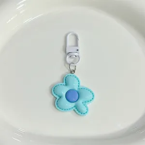 Close-up of cute light blue flower keychain pendant with purple center and white clasp.