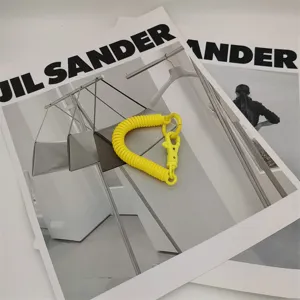 Détail de porte-clés à ressort jaune vif, accessoire de sac idéal et dragonne pratique.
