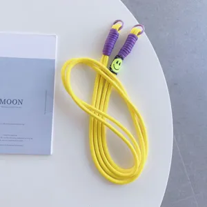 Yellow braided phone lanyard with purple ends and smiley face tag, stylish cross body strap.