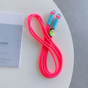 Close-up detail of neon pink phone lanyard with blue accents and cute smiley badge.