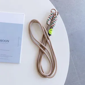 Beige crossbody phone lanyard with colorful braided ends and cute smiley face charm detail.